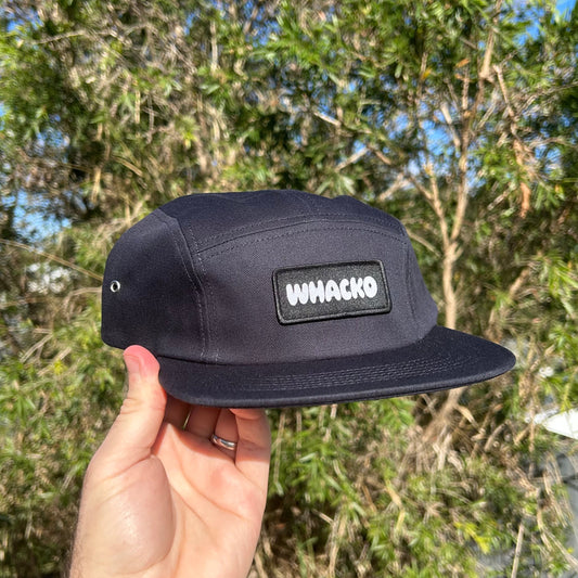 NAVY cap with 'WHACKO' logo held in front of a natural background